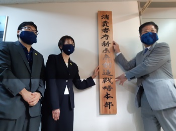 写真:縦1メートルほどの長さの木の看板に「消費者庁新未来創造戦略本部」の文字が書かれている。衛藤大臣と伊藤消費者庁長官が、左右から看板に手をかけている。