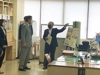 写真:職員の机の並ぶ執務室の一室を案内される衛藤大臣