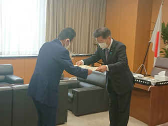 写真:鈴木浜松市長に、表彰状を両手で手渡す衛藤大臣。