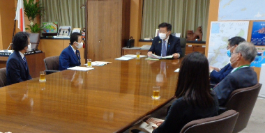 写真:大きな机のの半分を囲むように、6人が間隔をあけて座っている。