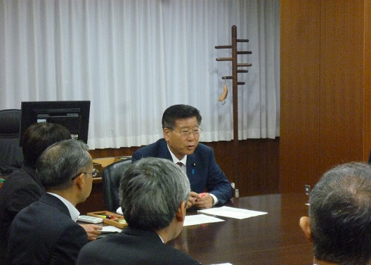 写真:写真奥、正面に衛藤大臣が座っている。同じ机の一角で、数名の職員が衛藤大臣に向かい合っている。