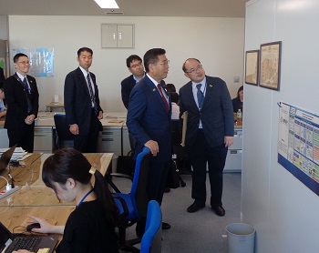 写真:壁に掛けられた額縁をのぞき込む衛藤大臣。