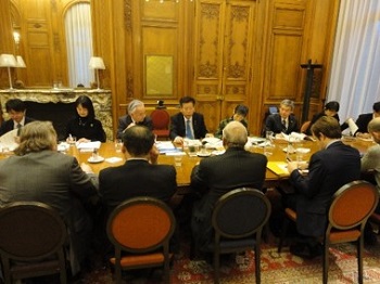 写真:大きな机の一角、10人ほどが向かい合って座っている。