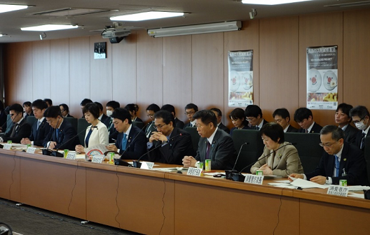 写真:並べた長机に着生している参加者。後ろにも椅子が配置され、20人強が座っている。