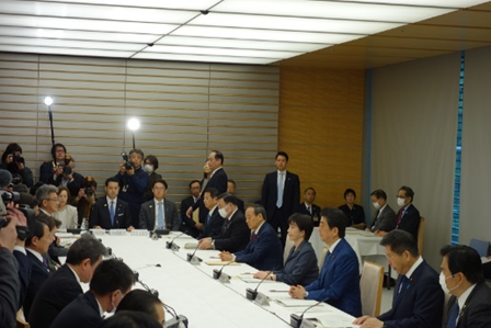 写真:大きな机を20人強が、囲むように座っている。