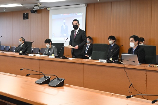写真:横並びに配置される会議机の前で、立ち上がり挨拶をする井上大臣