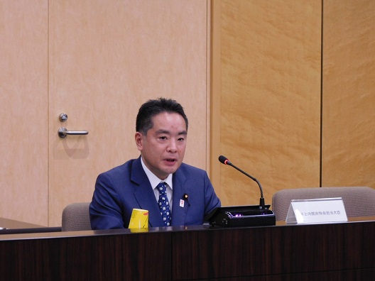 写真:演台の前に座り、発言する井上大臣