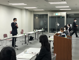 写真:横並びに座った相談員の前で向かい合うようにして立ち上がり、話をしている井上大臣