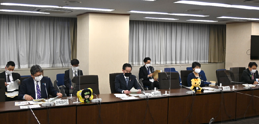 写真:会議机の中心に井上大臣が座る。左隣の席机の上には、マスコットキャラクターであるいややんのぬいぐるみが置いてある。