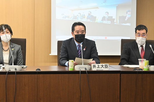 写真:会議用の長机に3人が着席している。真ん中に井上大臣が座り、発言している。