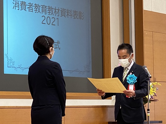 写真:受賞者と向かい合い、表彰状を読みあげる井上大臣。