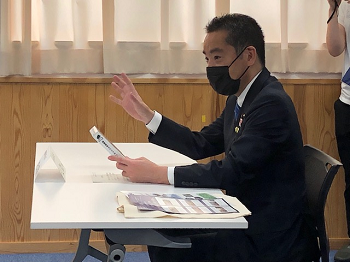 写真:席に付き、資料を手に、話を聞く井上大臣。