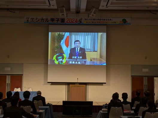 写真:壇上のスクリーンで、伊東大臣のビデオメッセージが上映されている