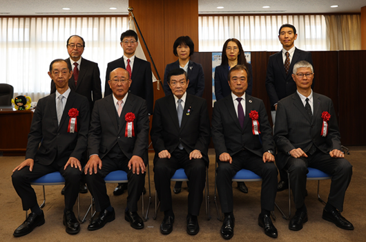 一番中央に座っている伊東大臣。受賞者の皆さんが、伊東大臣の両隣に座り、また、後ろに立って映っている。