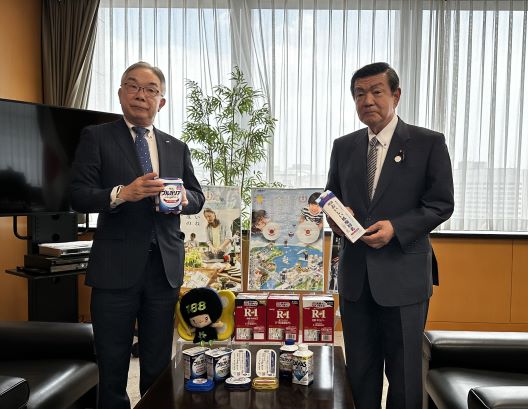 明治の商品を手にした八尾社長と伊藤大臣