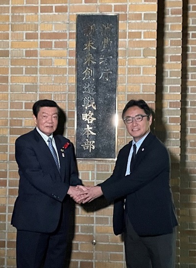 写真:消費者庁新未来創造戦略本部の看板の前で握手をする伊東大臣と後藤田徳島県知事