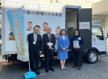 写真:フードバンク徳島の移動子ども食堂のトラックのの横に立つ自見大臣
