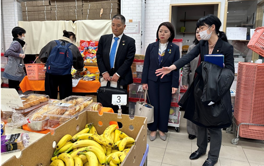 写真:食品が並ぶ名、説明を受ける自見大臣