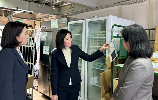 写真:女性職員より説明を受ける自見大臣