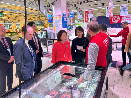写真:スーパーの冷凍庫の前で説明を受ける大臣