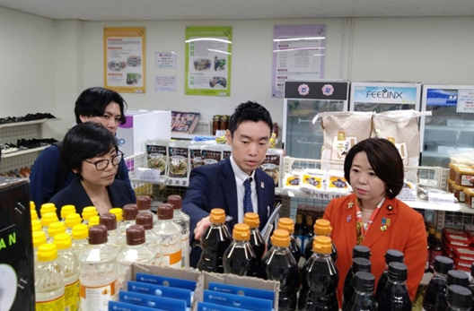 写真:商品の並んだ棚の前で説明を受ける自見大臣