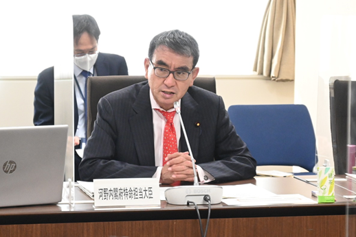 写真:席に着き、発言する大臣。机の上には、「内閣府特命担当大臣」の札が置かれている。大臣の横は、透明のパーテーションで区切られている。