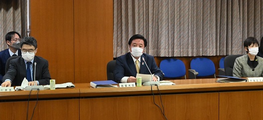 写真:横長の会議机が並べられ、中央に若宮大臣が座っている。写真左に中川座長、右に伊藤消費者庁長官が、距離を開けて着席している。