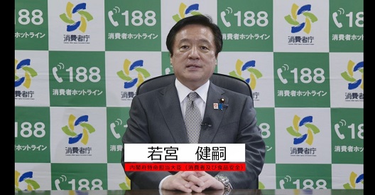 写真:消費者庁ロゴマークの並んだバックボードの前に座り、話をする若宮大臣