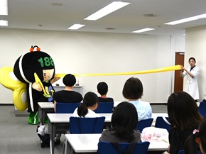 写真:白衣を着た講師とイヤヤンのデモンストレーション