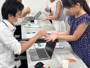 写真:子どもたちの手の汚れを測っている様子