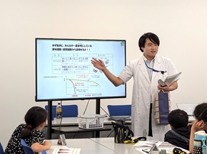 写真:講師役である職員たちが、子どもたちに説明をしている様子