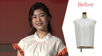 写真:袖にオレンジのギャザーフリルをあしらった白いシャツを着た女性。