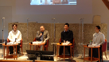 写真:一人掛けのソファと机のセットが4つ並び、4人の男女が座っている。それぞれの間は、透明のパーテーションで区切られている。